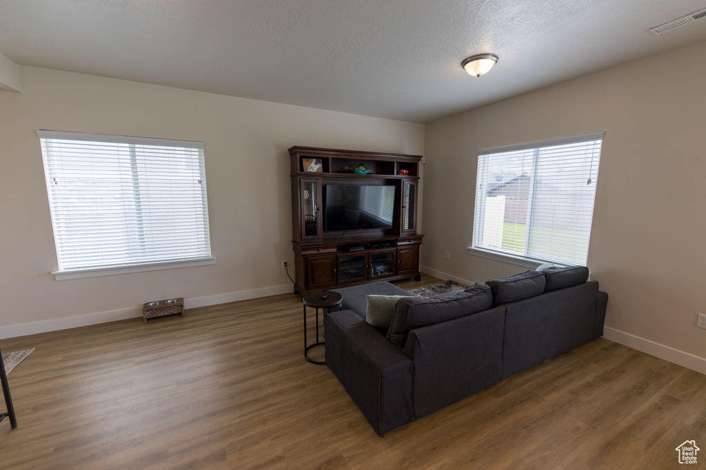 Living room with baseboards, visible vents, and wood finished floors