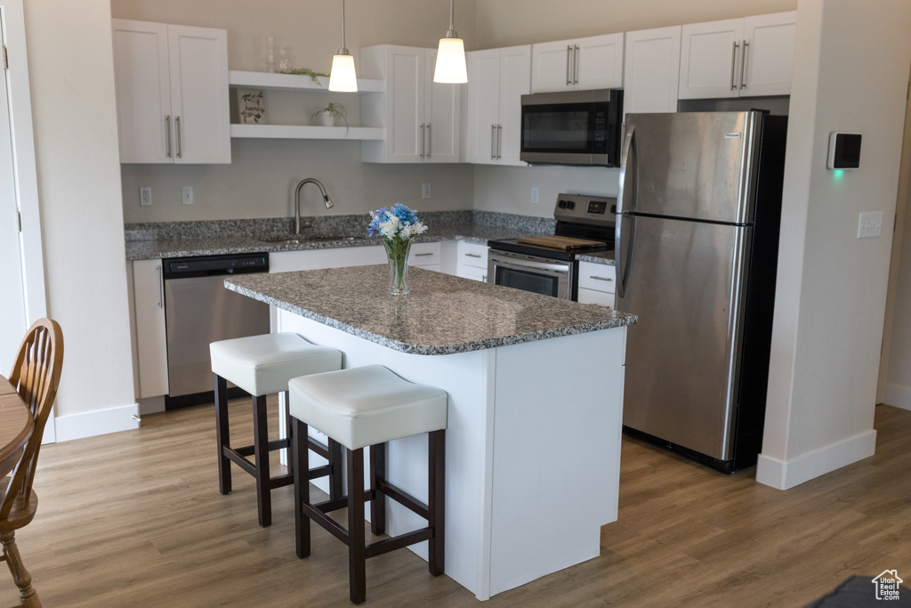 Kitchen with baseboards, stainless steel appliances, open shelves, and a sink