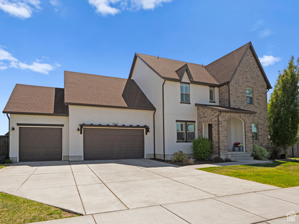 Traditional-style home with a front lawn, stucco siding, driveway, and a garage