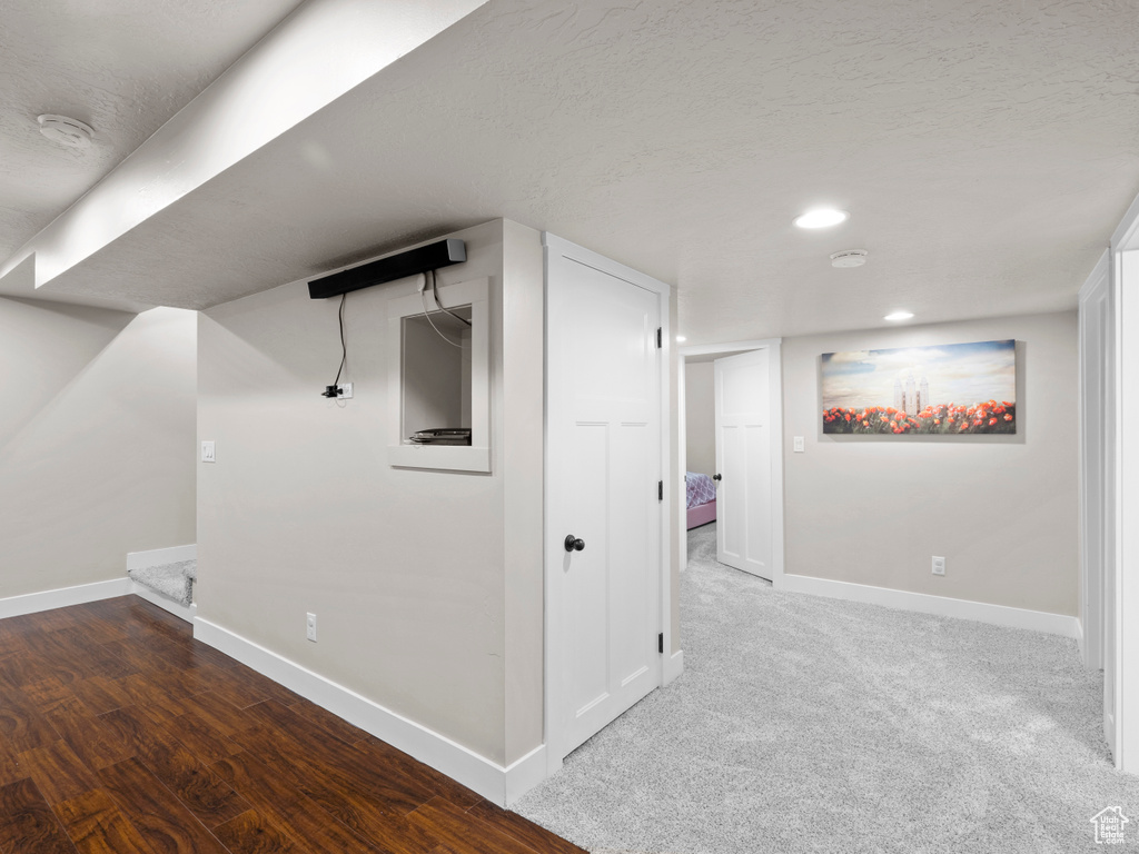 Finished below grade area featuring wood finished floors, baseboards, and a textured ceiling