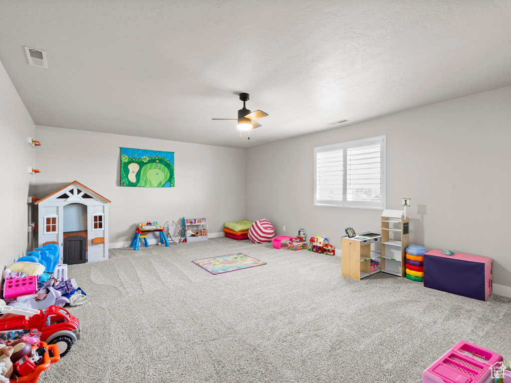 Rec room with carpet flooring, baseboards, a ceiling fan, and visible vents