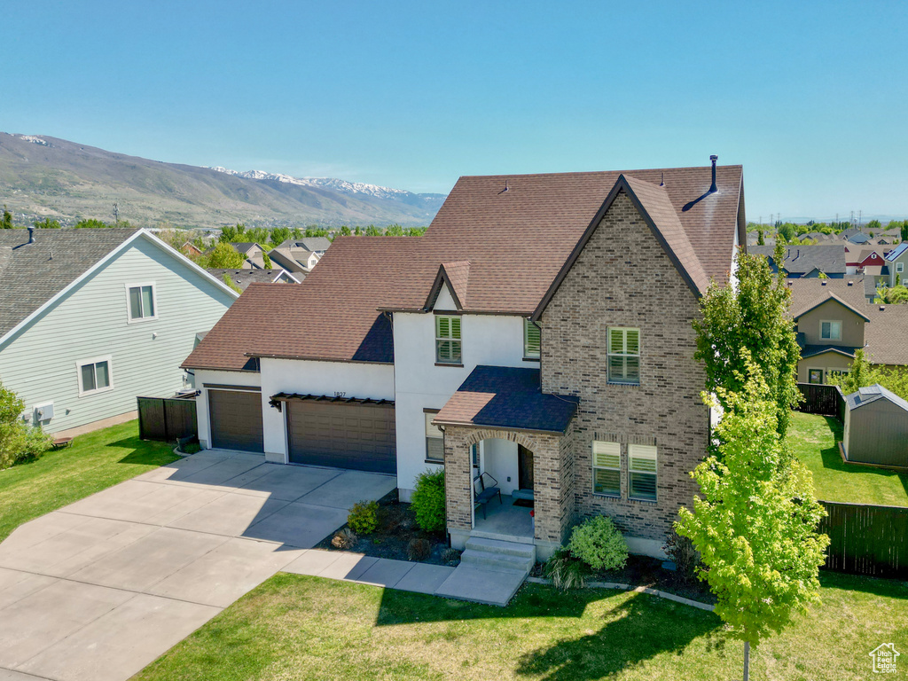 View of front facade featuring a front yard, an attached garage, stucco siding, and driveway