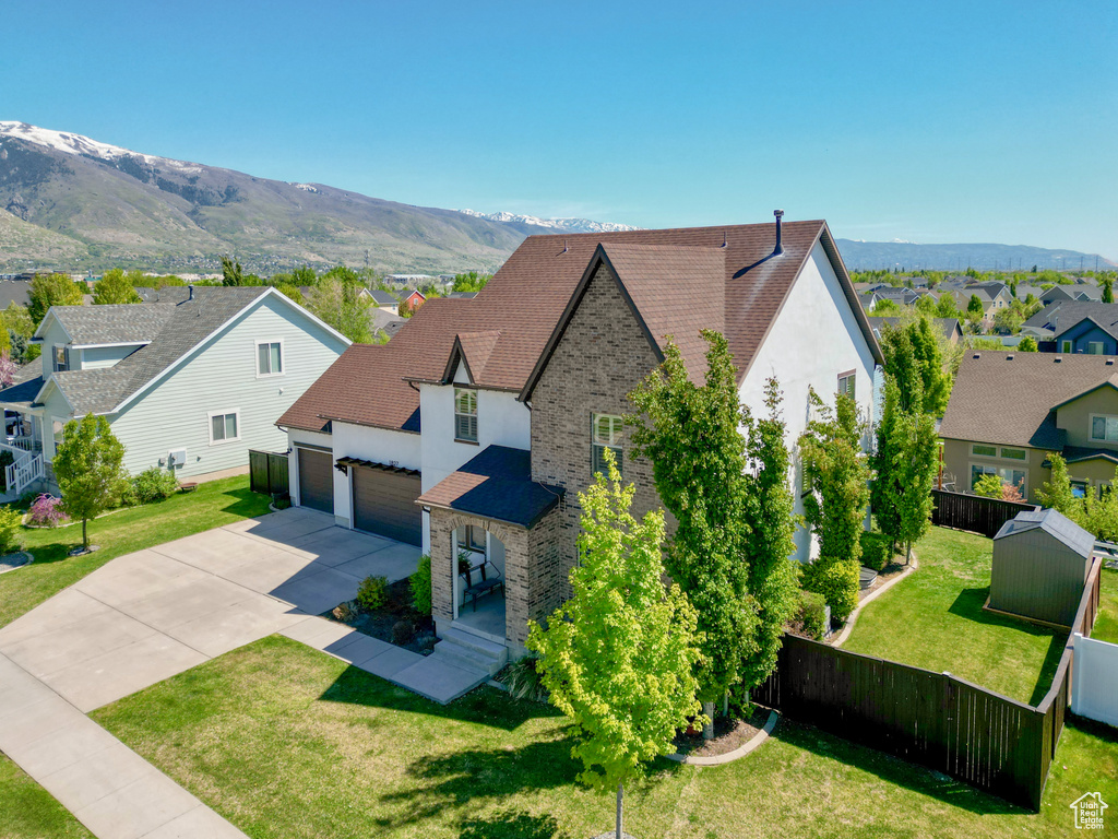 Exterior space with a mountain view, a residential view, a garage, fence, and concrete driveway
