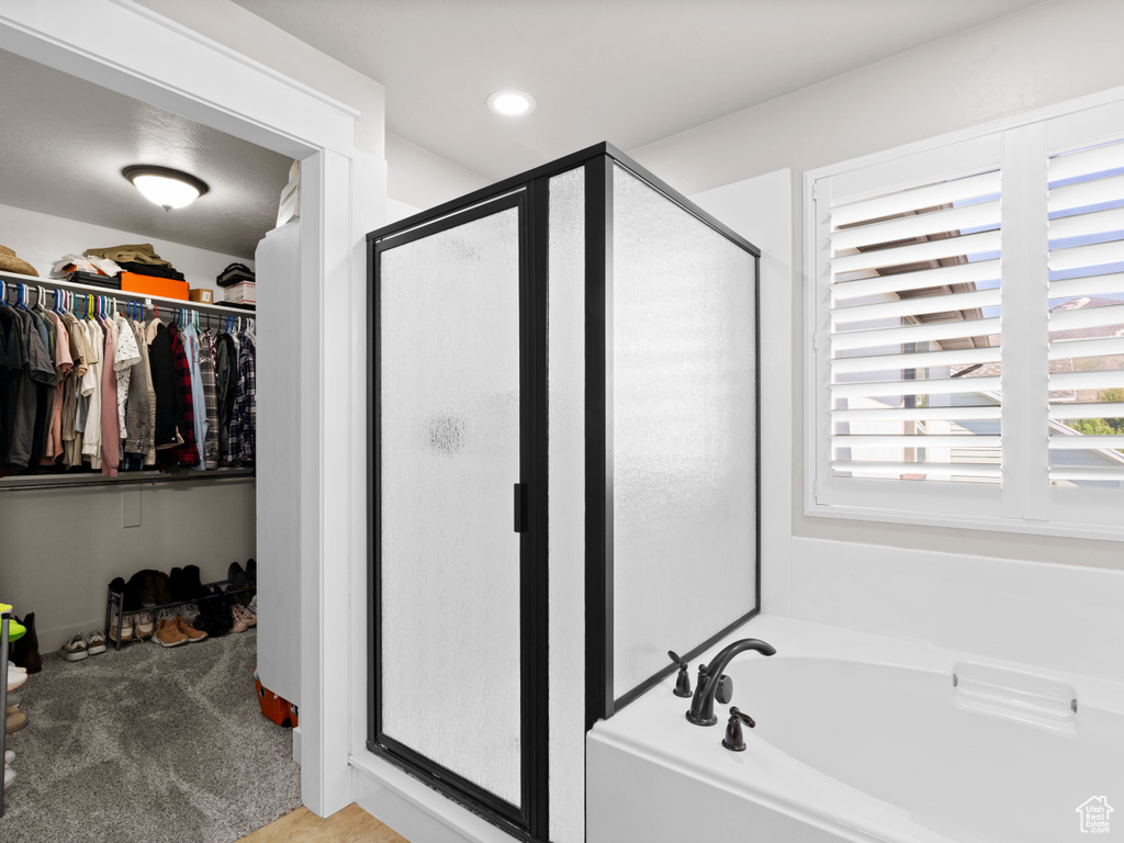 Full bathroom featuring a walk in closet, a shower stall, a bath, and recessed lighting