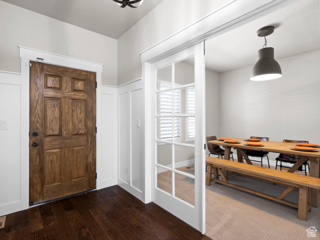 Foyer with dark wood-style flooring, a decorative wall, and a wainscoted wall