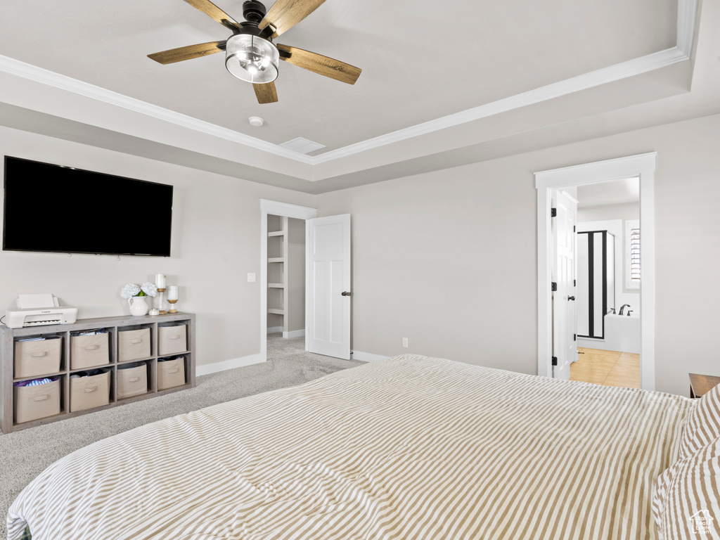 Carpeted bedroom with a tray ceiling, crown molding, ensuite bathroom, and baseboards