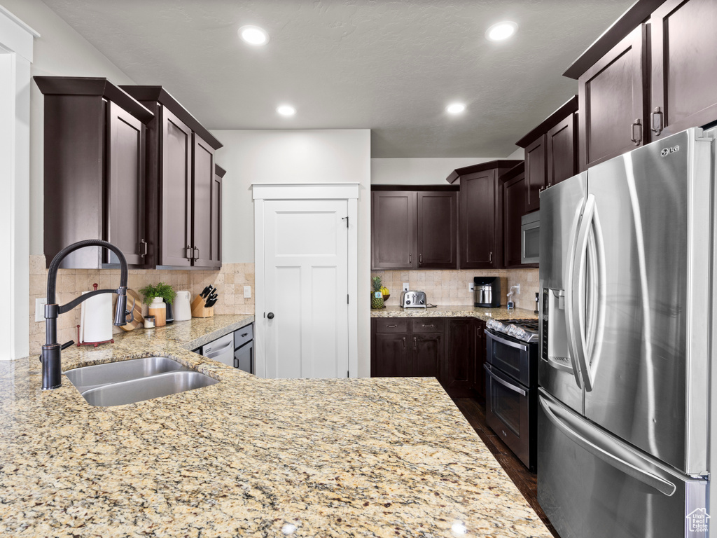 Kitchen with a sink, dark brown cabinetry, appliances with stainless steel finishes, decorative backsplash, and recessed lighting