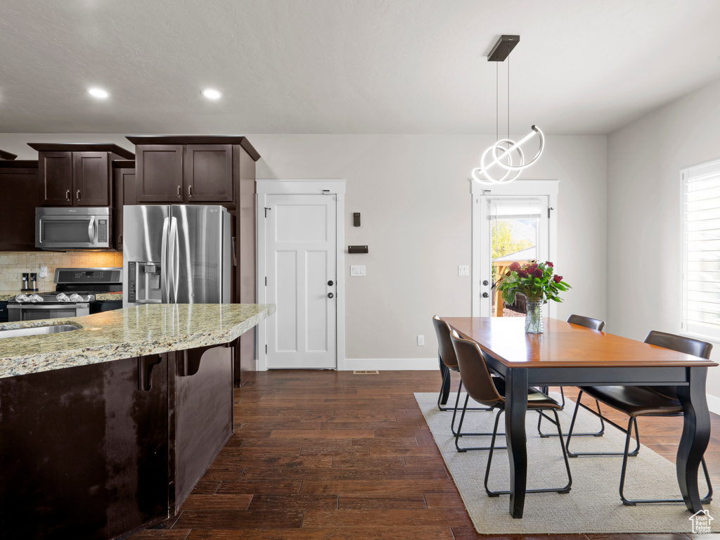 Dining room with dark wood-style flooring, baseboards, and recessed lighting