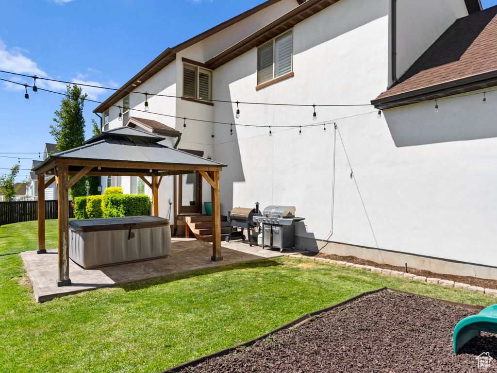 Rear view of property with a patio, fence, a lawn, a hot tub, and a gazebo
