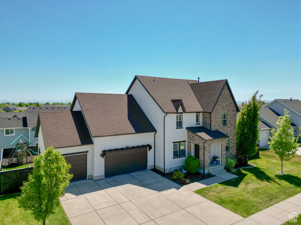 View of front of property featuring concrete driveway, stucco siding, a front lawn, and a garage