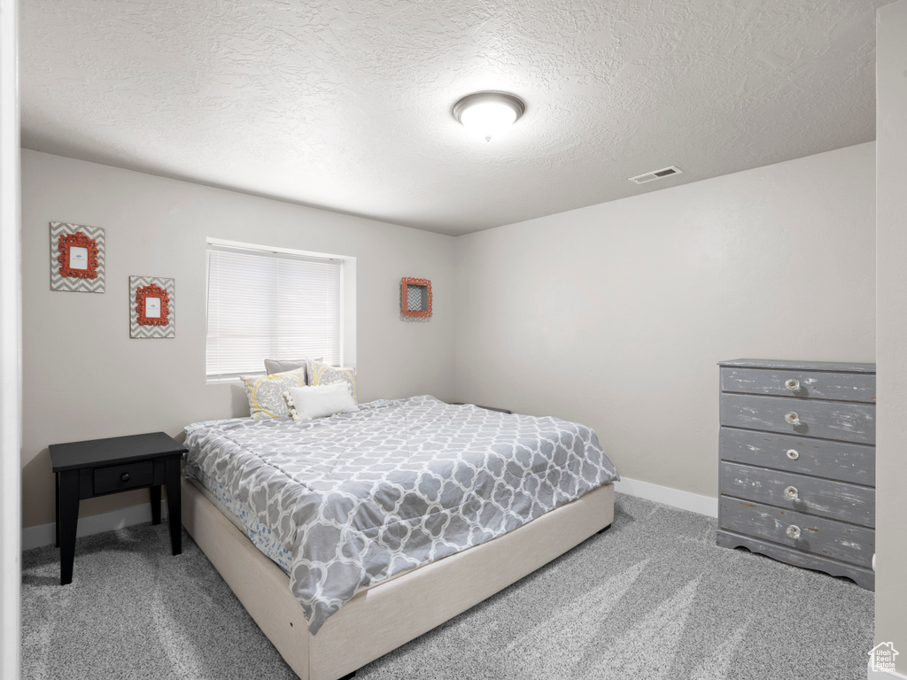 Bedroom featuring a textured ceiling, visible vents, baseboards, and carpet floors