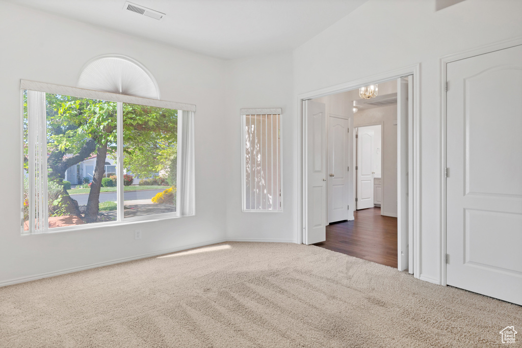 Unfurnished bedroom featuring carpet flooring, visible vents, baseboards, and a notable chandelier
