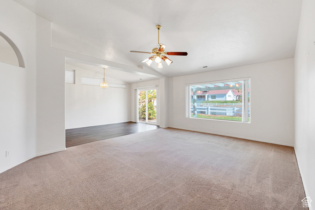 Unfurnished room with carpet, vaulted ceiling, ceiling fan, arched walkways, and baseboards