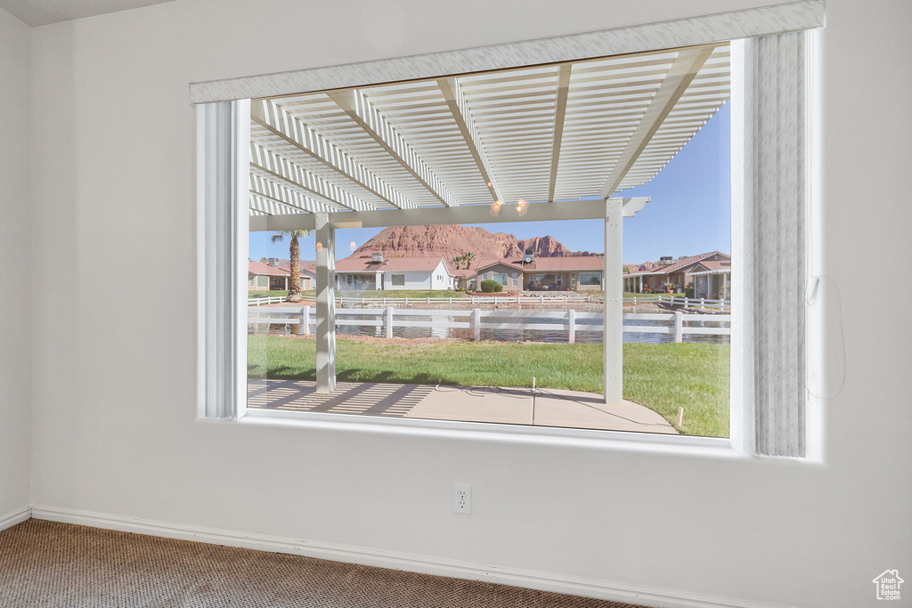 Carpeted spare room featuring plenty of natural light, a residential view, and baseboards