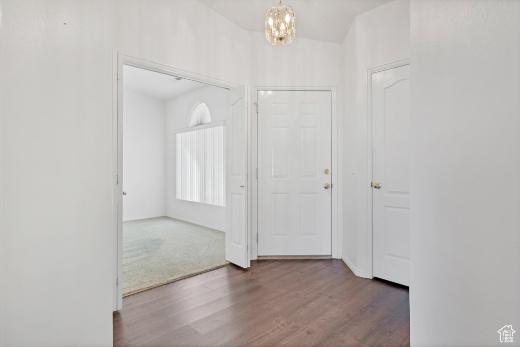 Interior space with an inviting chandelier, dark wood-type flooring, and lofted ceiling