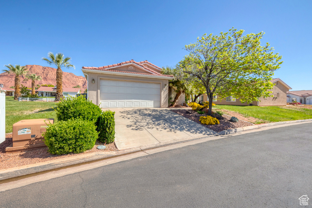 View of front of home featuring a tile roof, an attached garage, a front yard, and driveway