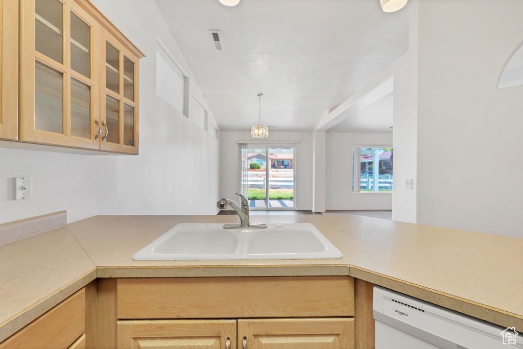 Kitchen featuring light brown cabinetry, glass insert cabinets, dishwasher, a sink, and light countertops