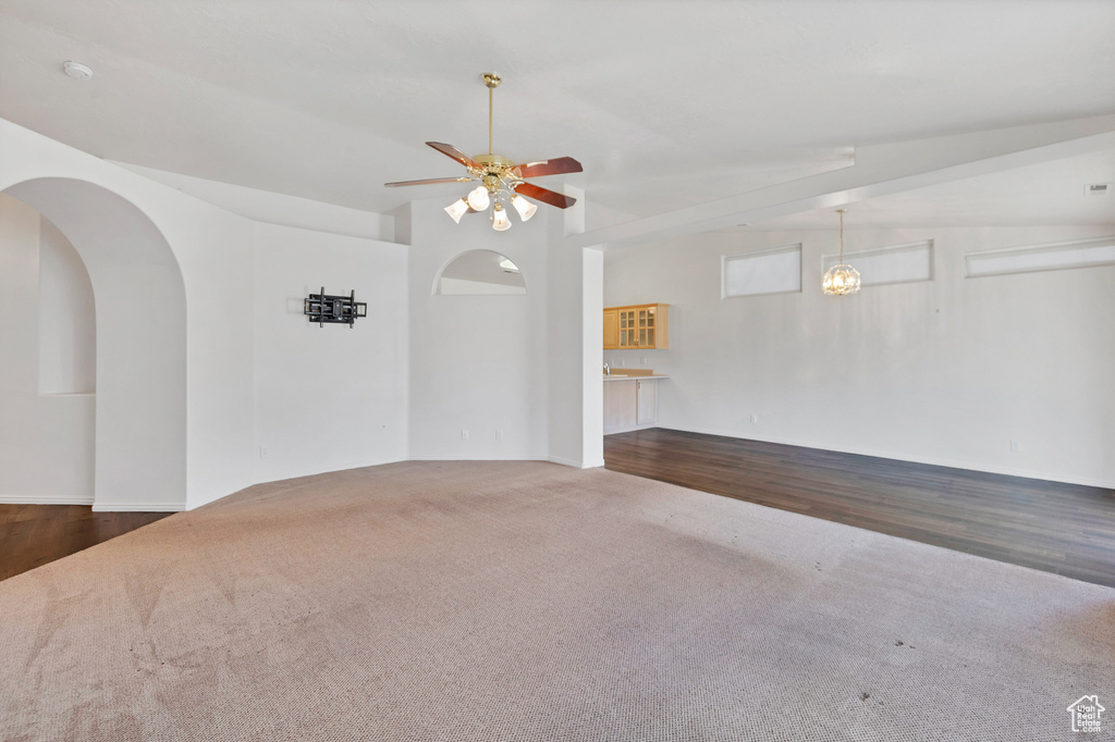 Unfurnished room featuring ceiling fan, carpet flooring, and arched walkways