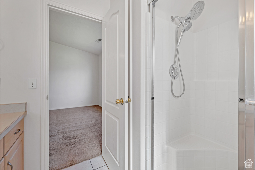 Full bath with tile patterned floors, vanity, and a tile shower