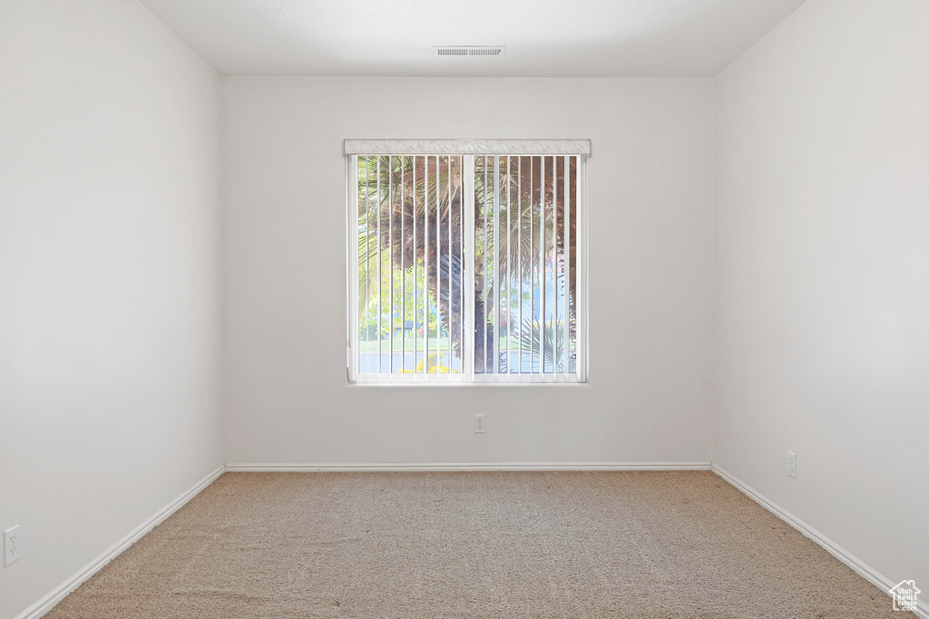 Carpeted empty room with visible vents, baseboards, and a healthy amount of sunlight