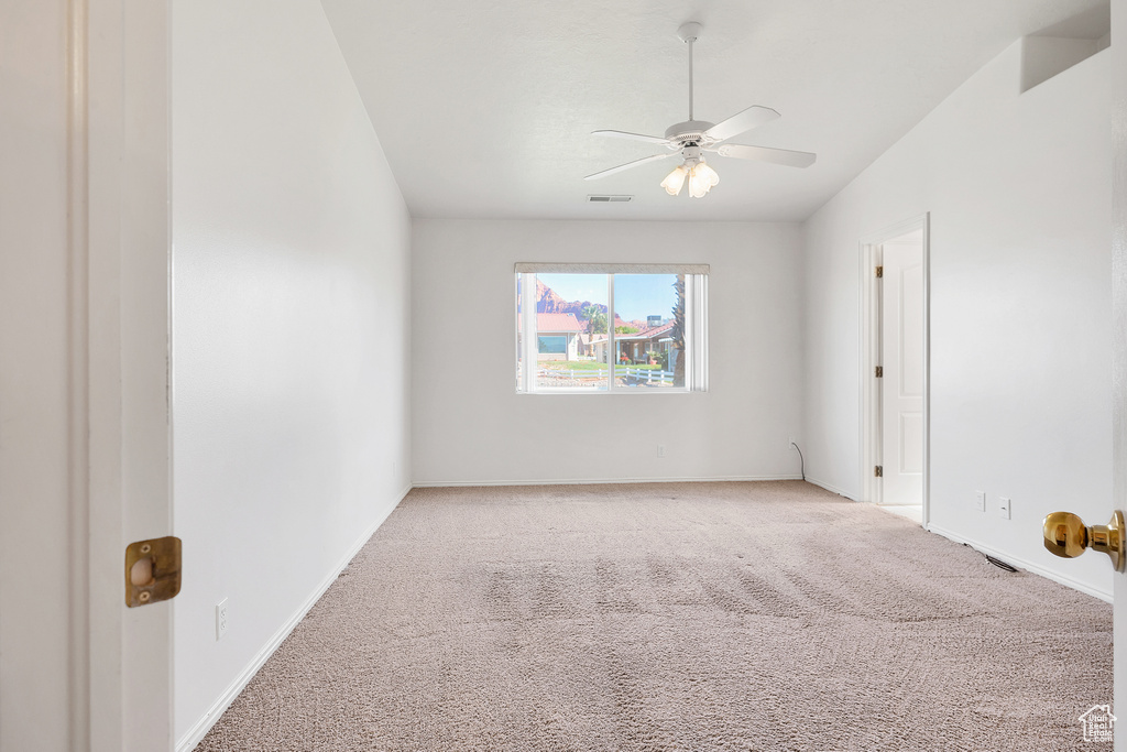 Empty room with light carpet, baseboards, a ceiling fan, and visible vents