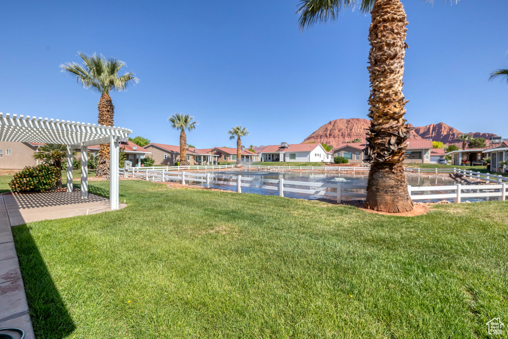 View of yard featuring a pergola, fence, a mountain view, and a residential view