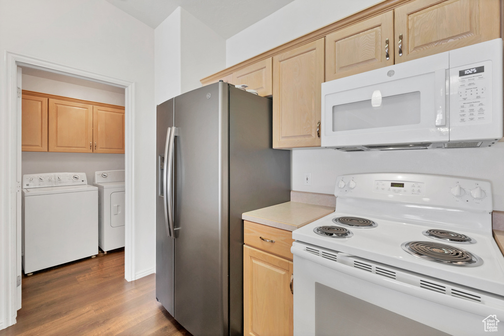 Kitchen featuring white appliances, independent washer and dryer, wood finished floors, light brown cabinetry, and light countertops