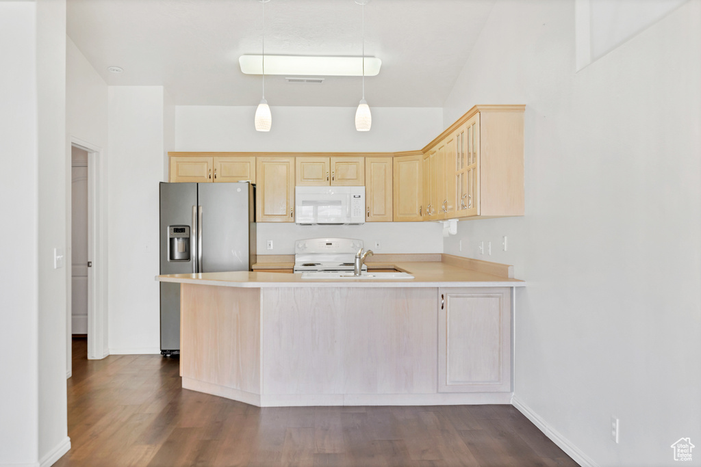 Kitchen with a peninsula, light brown cabinetry, dark wood-type flooring, white appliances, and light countertops