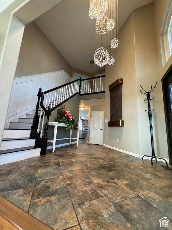 Entryway with an inviting chandelier, a high ceiling, stone tile floors, stairway, and baseboards