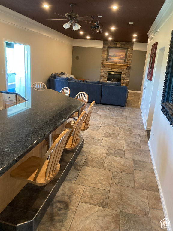 Dining space with a fireplace, stone tile floors, ornamental molding, and baseboards