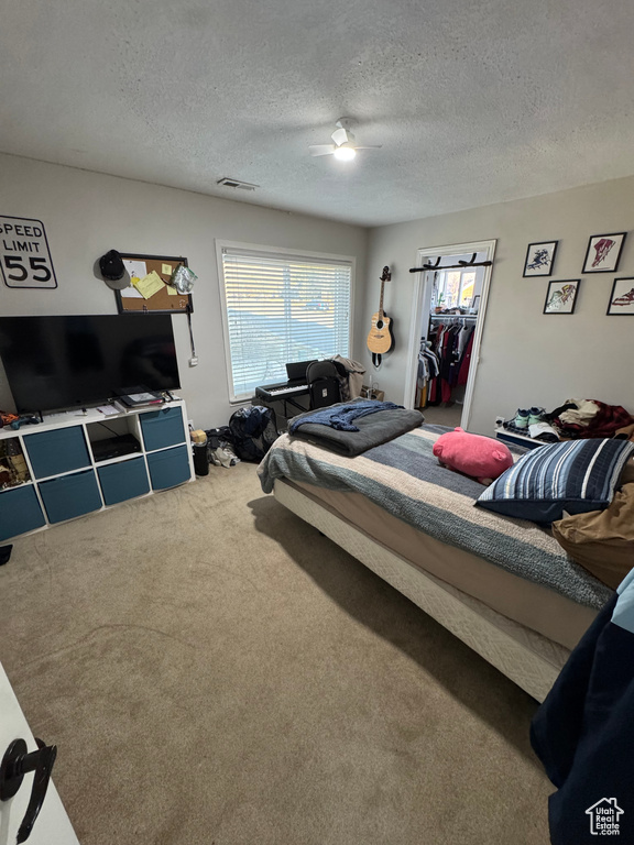 Bedroom with carpet, a ceiling fan, visible vents, and a textured ceiling