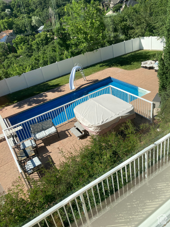 View of pool featuring a fenced in pool, a water slide, and a fenced backyard