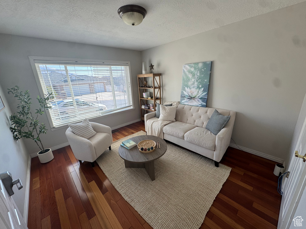 Living area featuring a textured ceiling, baseboards, and wood finished floors