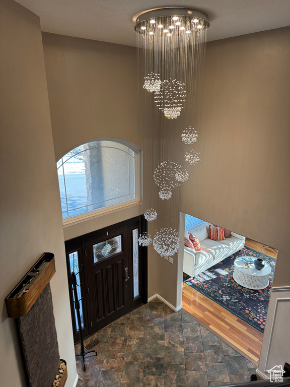 Foyer entrance featuring an inviting chandelier, baseboards, and stone finish floor