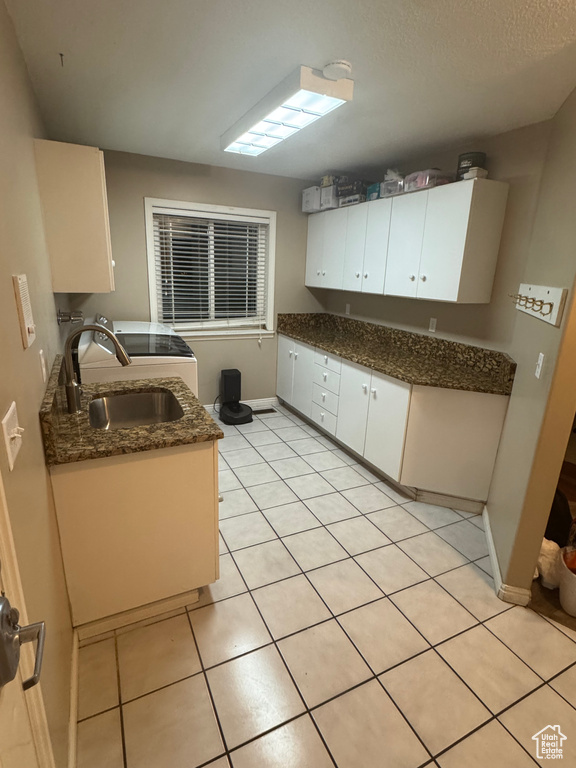 Kitchen with a sink, light tile patterned flooring, white cabinetry, and baseboards