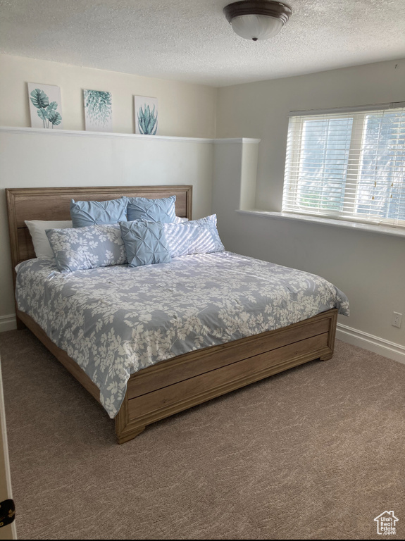 Carpeted bedroom featuring a textured ceiling and baseboards