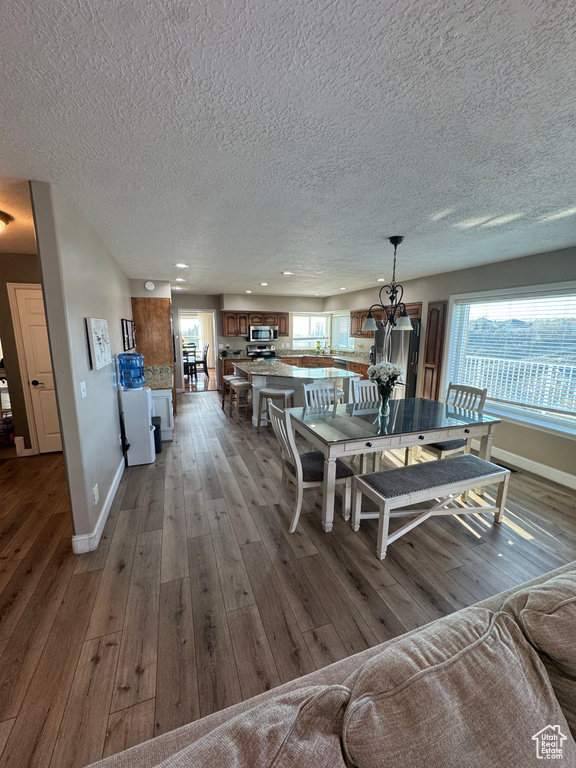 Dining room with recessed lighting, a textured ceiling, baseboards, and hardwood / wood-style flooring