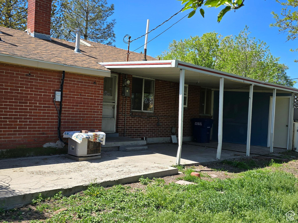 Rear view of house with a shingled roof, brick siding, and a chimney