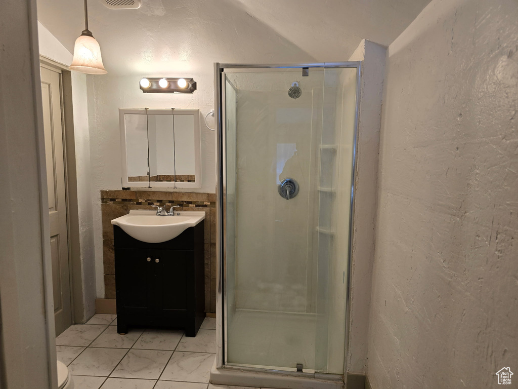 Bathroom with vanity, a textured wall, a shower stall, and marble finish floor