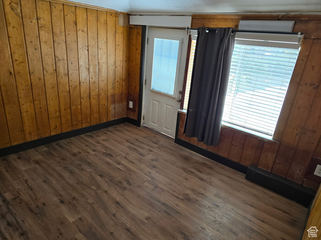 Unfurnished room featuring wood walls, plenty of natural light, and wood finished floors