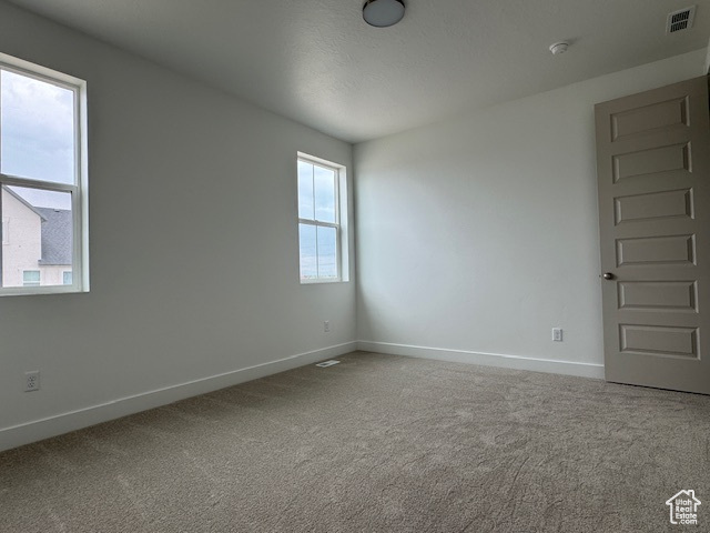 Carpeted spare room featuring baseboards and visible vents