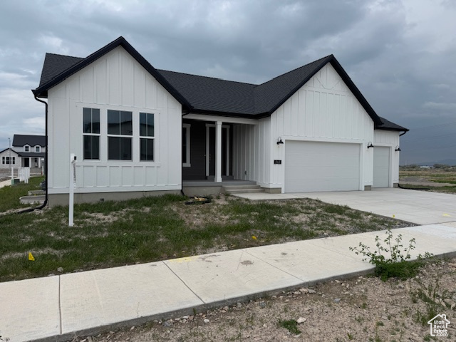 View of front of house featuring covered porch, board and batten siding, a garage, and concrete driveway