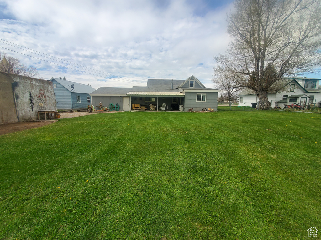Back of house with fence and a lawn
