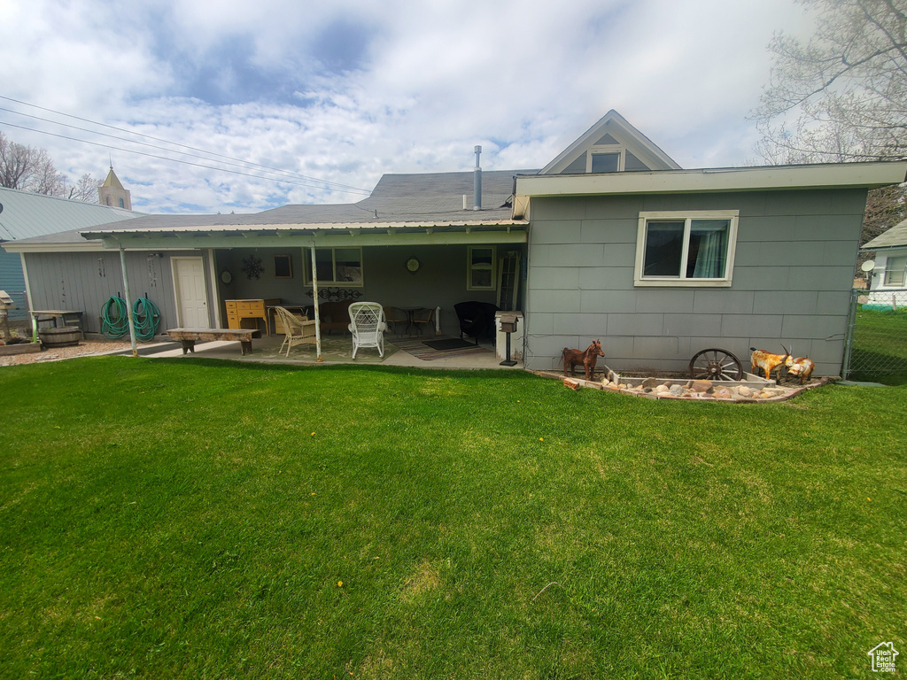 Back of property featuring a lawn, a patio area, and fence