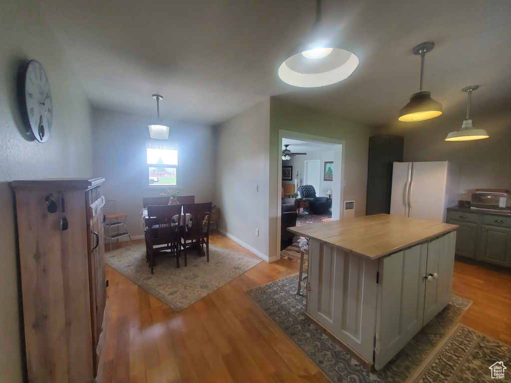 Kitchen featuring freestanding refrigerator, a center island, butcher block counters, ceiling fan, and light wood-type flooring
