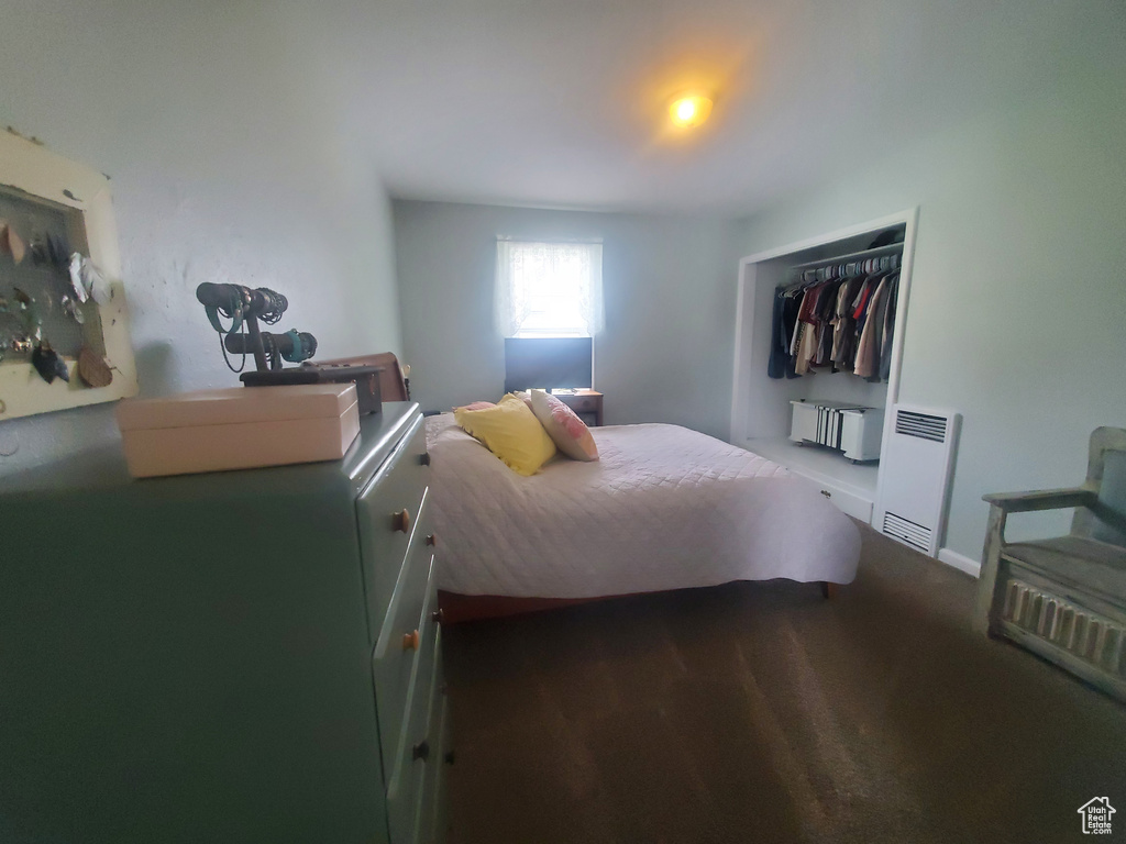 Bedroom with heating unit, a closet, and baseboards