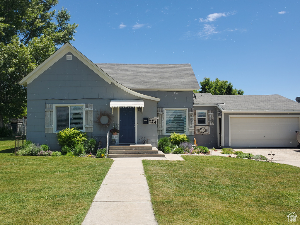 View of front of property with a garage, a front yard, concrete driveway, and a shingled roof
