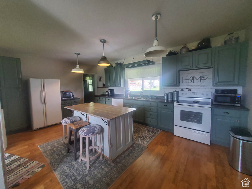 Kitchen with wooden counters, a sink, pendant lighting, dark wood finished floors, and white appliances
