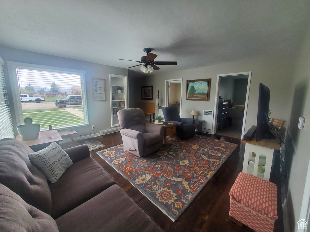 Living room featuring baseboards, visible vents, wood finished floors, and a ceiling fan