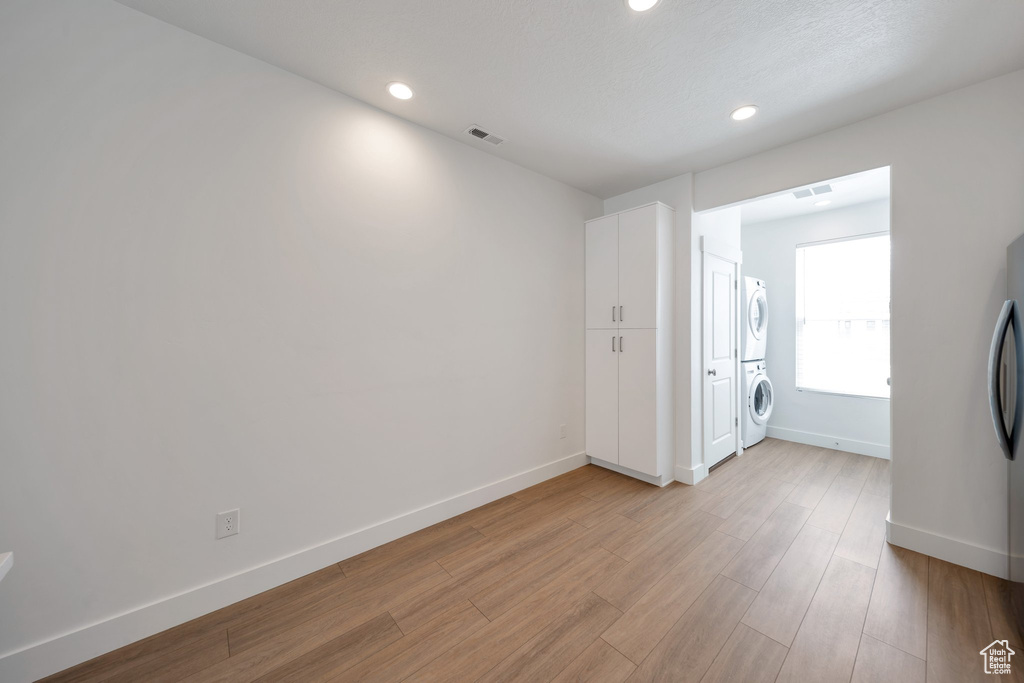 Unfurnished room featuring recessed lighting, baseboards, light wood finished floors, visible vents, and stacked washer and clothes dryer